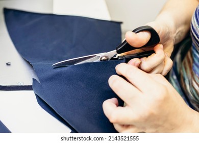Close up view of clothes cutting process. Female hands cutting clothes at workplace