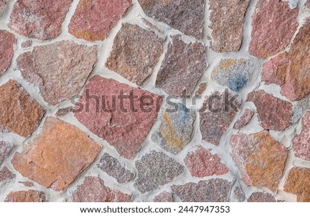 It's close up view of colorful wall. Its photo of multicolor stonewall. It is the photo of multicolored srone wall. its view of red sidewalk. It's view of mosaic color stones