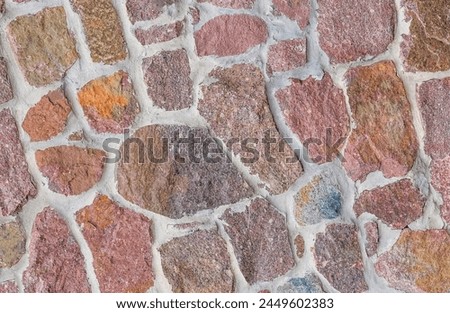 It's close up view of colorful wall. Its the photo of multicolor stonewall. It is photo of multicolored srone wall. its view of red sidewalk. It's view of mosaic color stones