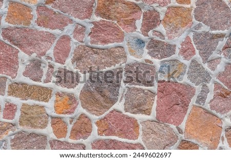 It's a close up view of colorful wall. Its photo of multicolor stonewall. It is photo of multicolored srone wall. its view of red sidewalk. It's view of mosaic color stones