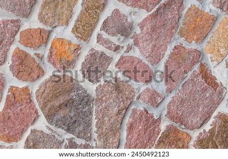 It's close up view of colorful wall. Its photo of multicolor stonewall. It is photo of the multicolored srone wall. its view of red sidewalk. It's view of mosaic color stones