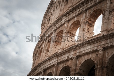 Close up view of the Colosseum in Rome, Italy. Grand arches, intricate stonework, historical significance, and timeless beauty. Sky overcast, no people in sight.
