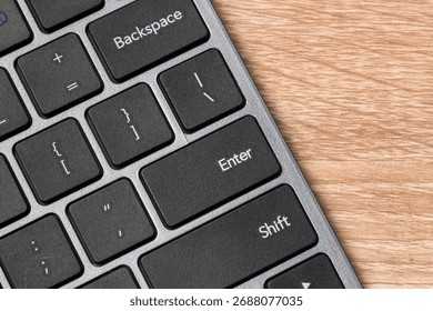 Close up view of a computer keyboard on wooden table with focus on Enter Key