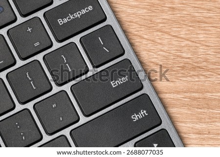 Close up view of a computer keyboard on wooden table with focus on Enter Key