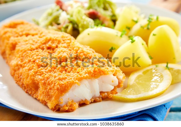 Close up view of crispy breaded fish served on\
plate with potatoes