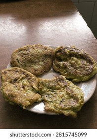 Close up view of crispy fried courgette fritters arranged neatly on a plate placed upon a warm natural wooden table surface.