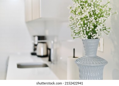 Close Up View Of Cute Tiny White Gypsophila Flowers In Grey Stylish Vase On The Kitchen Counter Top, No People. Modern Domestic Room Background