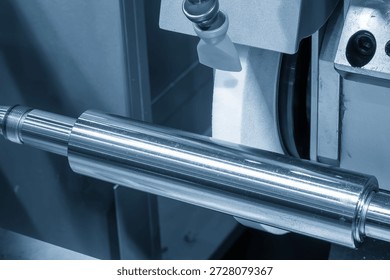 Close up view of a cylindrical grinding machine operating on metal shaft parts in a light blue industrial scene. Precision grinding and surface finishing process for high accuracy components, representing industrial manufacturing, mechanical engineering, and modern machining technology. Ideal for industrial, machining, and engineering background concepts.