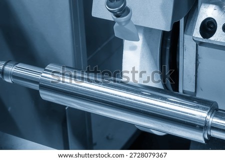 Close up view of a cylindrical grinding machine operating on metal shaft parts in a light blue industrial scene. Precision grinding and surface finishing process for high accuracy components, representing industrial manufacturing, mechanical engineering, and modern machining technology. Ideal for industrial, machining, and engineering background concepts.