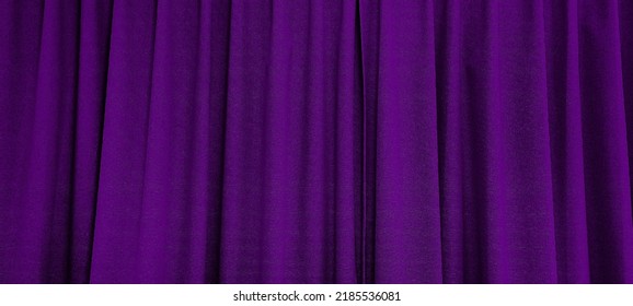 close up view of dark purple curtain in thin and thick vertical folds made of black out sackcloth fabric, panoramic view of drapery use as background. abstract theatre backgrounds and wallpapers.