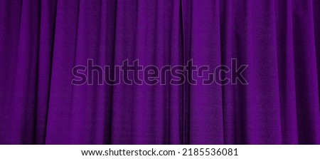 close up view of dark purple curtain in thin and thick vertical folds made of black out sackcloth fabric, panoramic view of drapery use as background. abstract theatre backgrounds and wallpapers.