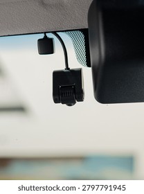 Close up view of a dash camera mounted on a car windshield with lens and mount visible inside the vehicle for a technology oriented shot