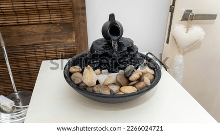 Close view of a decorative zen water fountain on top of a white wooden table