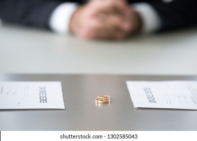 Close Up View Of Decree Paper And Rings On Table As Concept Of Couple Divorce, Family Split Up About To Sign Marriage Dissolution Document In Lawyers Office, Legal Separation Settlement Concept