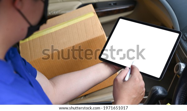 Close up view\
delivery man using digital tablet while sitting in van. Delivery\
service and shipping\
concept.