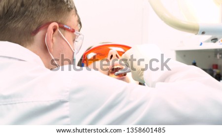 Close up view of dentist in latex gloves examining woman with opened mouth, dental care concept. Media. Back of a dentist who treats teeth of young woman patient.
