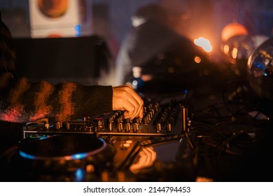 Close up view of a dj's hands playing the mixer while performing in a music festival. High quality photo
