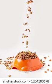 Close Up View Of Dog Food Granules Falling Into Plastic Bowl With Pet Food On White