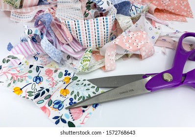 Close up view of a dressmaking scissors with a pile of scraps of printed patterned fabric - Shutterstock ID 1572768643