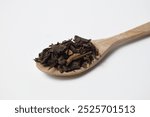 Close up view of dried tea leaves on wooden spoon. isolated on white background.