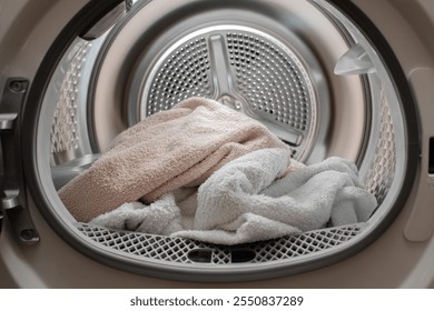 Close up view drying machine with washed and dried towels in and door open.