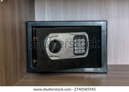 Close up view of electronic safe with keypad installed inside wooden cabinet. Home security and protection concept in modern apartment interior.
