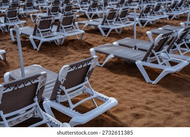 Close view of empty beach sunbeds with umbrella poles, resort vacation and leisure concept.