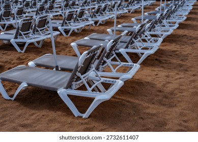 Close view of empty beach sunbeds with umbrella poles, resort vacation and leisure concept.