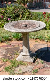 A Close Up View Of A Empty Concrete Bird Water Bath On The Side Of A Garden 