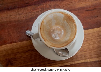 A Close Up View Of A Empty White Dirty Used Coffe Cup And Sourcer With A Small Amount Of Foam And Coffee At The Bottom 