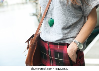 Close up view of a fashion girl wearing grey t-shirt, a heart shape necklace and red skirt