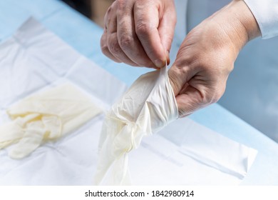 Close Up View For A Female 50 Years Old Doctor Putting On Surgical Gloves. Medical Exam Concept. Doctor Profession Conceptual.