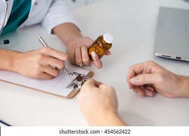 Close up view of female doctor hand holding bottle with pills and writing prescription. Healthcare, medical and pharmacy concept. - Powered by Shutterstock