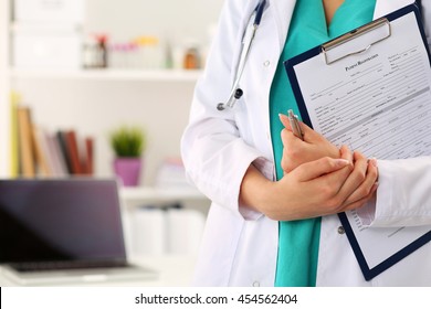 Close up view of female doctor hands holding clipping pad with patient registration form. Healthcare and medical service concept.