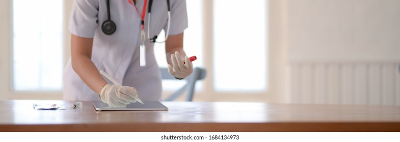 Close up view of female doctor writing blood tests on digital tablet while standing in examination room  - Shutterstock ID 1684134973