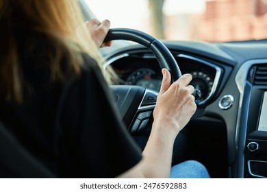 Close up view of female driver hands on steering wheel. Woman driving car at sunset. Inside view of modern vehicle moving on road