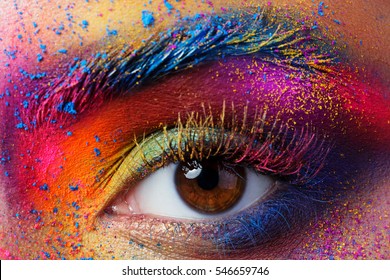Nahaufnahme des weiblichen Auges mit heller, mehrfarbiger Mode. Holi indianisches Farbfestival inspiriert. Studio-Makroaufnahme