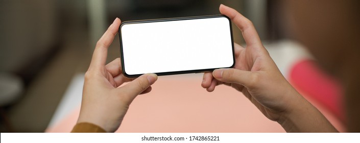 Close up view of female freelancer relaxing with horizontal mock-up smartphone in home office  - Shutterstock ID 1742865221