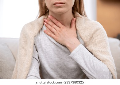 Close up view of female hand on neck, suffering from sore throat. Cropped view of sick woman feel discomfort in chest, painful, difficult to swallow. Concept of tonsillitis, angina, pectoris - Shutterstock ID 2337380325