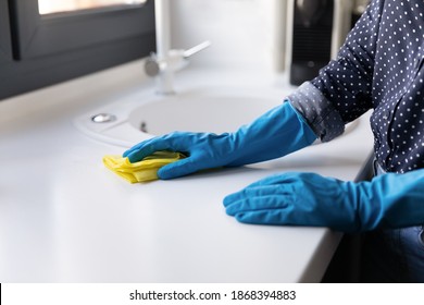 Close Up View Of Female Hands In Latex Rubber Gloves Rubbing Wiping Cleaning White Kitchen Counter With Soft Rag. Professional Cleaning Company Service. High Quality Household Goods For Daily Chores