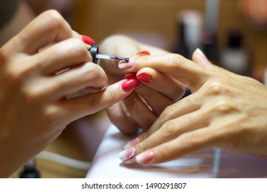 Close up view female nail painting  Manicurist applying transparent varnish forefinger nail during final step her work 