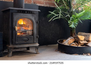 Close up view of firewood near black metal fire place in cozy living room. Concept of heating the house in winter season. Modern and energy efficient fireplace indoors apartment