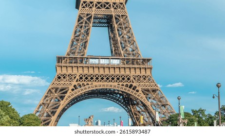Close up view of first section of the Eiffel Tower with tourists on observation deck timelapse in Paris, France. Sunny summer day with blue clody sky