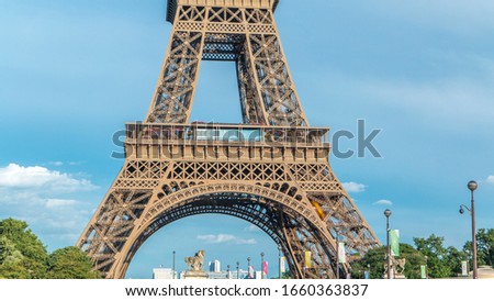 Close up view of first section of the Eiffel Tower with tourists on observation deck timelapse in Paris, France. Sunny summer day with blue clody sky