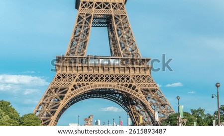 Close up view of first section of the Eiffel Tower with tourists on observation deck timelapse in Paris, France. Sunny summer day with blue clody sky