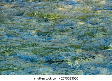 Close Up View Of A Flowing Creek With Pristine Clear Water Running Over Colorful Rocks.	
