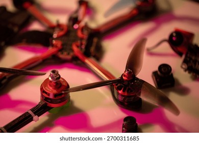 close up view of an fpv drone assembly showcasing motors, propellers, and various electronic parts arranged on a surface, illuminated with vibrant colors, neutral background, clear negative space