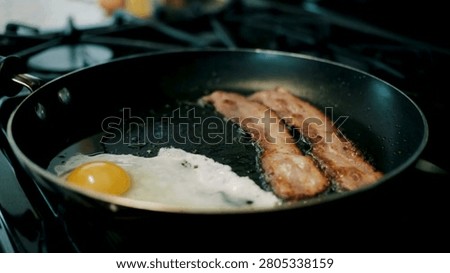 Close Up view Of Fried Eggs And Bacon Strips For Breakfast. Delicious cooked bacon strips, Close-up. Shot of pork bacon slices on a hot frying pan.
