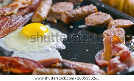 Close Up view Of Fried Eggs And Bacon Strips For Breakfast. Delicious cooked bacon strips, Close-up. Shot of pork bacon slices on a hot frying pan.