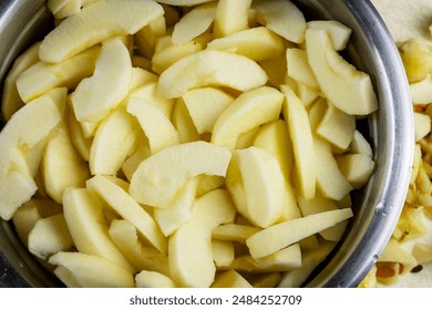 Close up view of gala apple slices in salt water in stainless bowl.  Preparation for a pie.  Scraps nearby. - Powered by Shutterstock